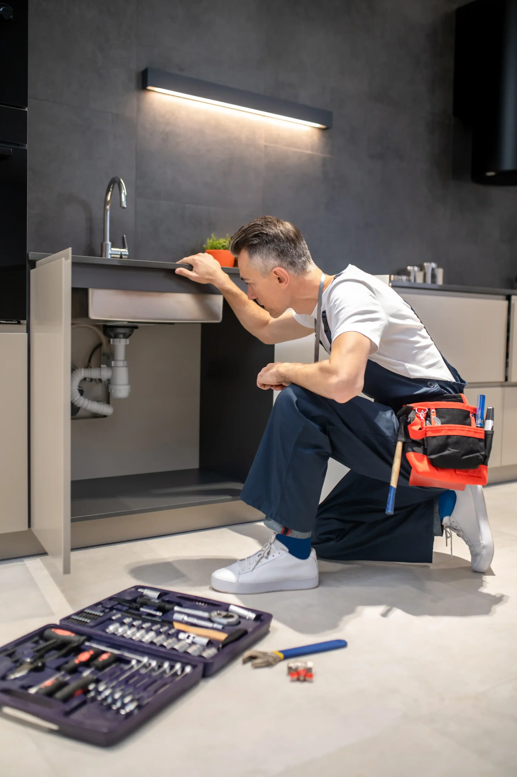 Plombier Namur inspectant une installation sous évier dans une cuisine moderne